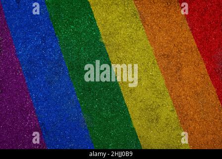 Regenbogenfarbene LGBT-Stolzflagge auf Asphalt, Draufsicht. Hochauflösender strukturierter Hintergrund aus bunt gestreiftem Asphalt, von oben betrachtet. Stockfoto