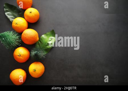 Zitrusfrüchte auf grauem Hintergrund. Mandarinen mit Blättern. Weihnachtsfrüchte. Stockfoto