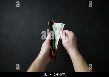 Die Hände nehmen Geldscheine aus einer Geldbörse auf grauem Hintergrund heraus. Fremdwährung. Stockfoto
