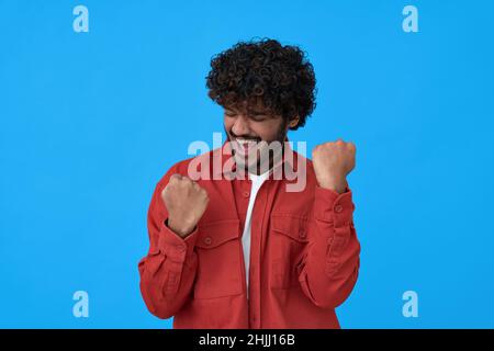 Aufgeregt junger indischer Mann Sieger feiert Sieg isoliert auf blauem Hintergrund. Stockfoto