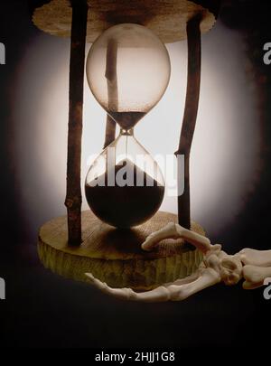 Stunden-Timer aus Glas, gehalten von einer Skeletthand Stockfoto