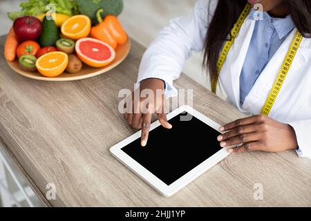 afroamerikanische Ernährungsberaterin arbeitet an digitalen Tablette, Kalorienzählen oder Schreiben Diät-Plan, kopieren Raum Stockfoto