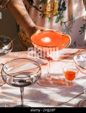 Mädchen hält Sommer Rhabarber Erdbeere Spritz Cocktail auf rosa Marmor Hintergrund. Mädchen Party Drink Ideen. Brunch Cokctail Ideen. Vertikale Aufnahme. Wählen Stockfoto