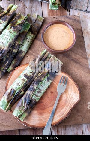 Gegrillter Fischkuchen aus gemahlenem Makrelenfisch, gemischt mit Gewürzen, dann in Bananenblätter gewickelt, über Holzkohle gegrillt, mit Erdnusssoße gegessen Stockfoto