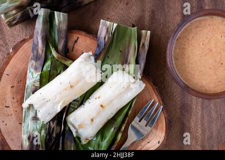 Gegrillter Fischkuchen aus gemahlenem Makrelenfisch, gemischt mit Gewürzen, dann in Bananenblätter gewickelt, über Holzkohle gegrillt, mit Erdnusssoße gegessen Stockfoto