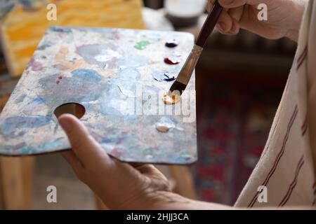 Künstler hält rechteckige Palette, mit Pinsel, mischen Farben Stockfoto