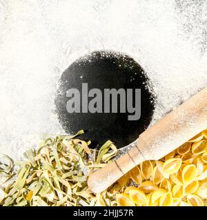 Frisch gekochte Pasta liegt auf einer dunklen, mit Mehl bestäubten Oberfläche. Italienische Pasta. Tagliatelle. Rohe Pasta. Italienische Pasta Rezept. Draufsicht, Kopierbereich. Stockfoto