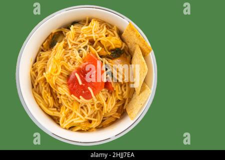 Draufsicht auf köstliche Nudeln mit Gemüse in einer Schüssel mit Tortilla-Chips auf grünem Hintergrund serviert Stockfoto
