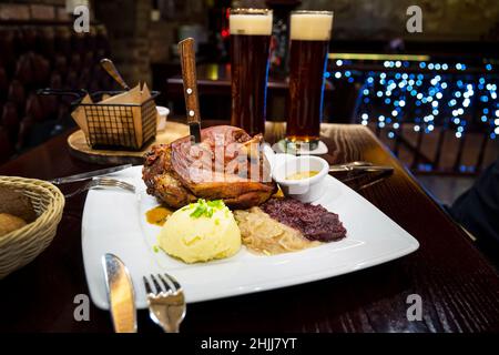Tschechische Gericht - Veprevo Knie in einem Gericht mit Soße Schweinefleisch Knie mit Kartoffeln und Honig Senf. Eine große Portion gegrilltes Schweinefleisch und Bier auf dem Tisch im Stockfoto