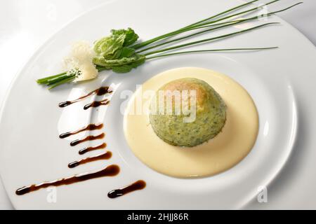 Gemüseflan mit Fondue Fontina Käse in weißem Teller mit Kräutern, italienische Gerichte Rezepte Stockfoto