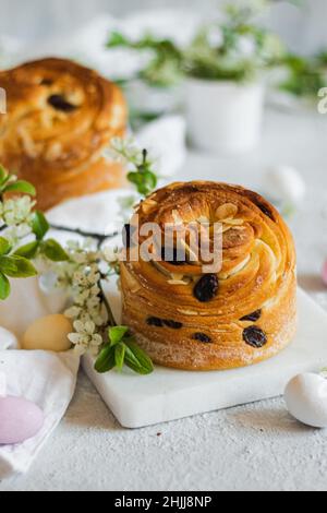 Frohe Ostern. Traditionelle Osterkuchen, hausgemachtes Kraffin mit Rosinen, kandierte Früchte. Kirschblüte auf weißem Holzhintergrund. Selektiver Fokus.Schließen Stockfoto