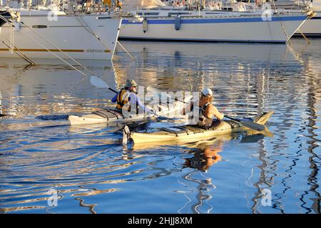 Villajoyosa Alicante Spain 01.30.22 Szene am frühen Morgen. Zwei Kanufahrer reden, paddeln über einen Yachthafen.Schwimmwesten. Reflexionen im Meer. Vertäut Stockfoto