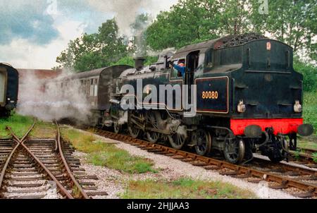 Ehemalige British Railways Standard Class 4 2-6-4 No 80080 Panzerlokomotive auf der Midland Railway in Butterley. Abfahrt mit einem Personenzug. Stockfoto