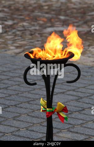 Im Freien brennen dekorative Fackeln mit Gläubigen Flieder, die in den Farben der litauischen Staatsflagge dekoriert sind Stockfoto