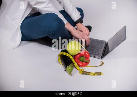 Gesunde Ernährung und Diät-Konzept - natürliche Nahrung auf dem Tisch.gesunde Ernährung, Ernährung, Gemüse. Ein Mann sitzt vor einem Computer, macht einen Plan für eine gesunde Stockfoto