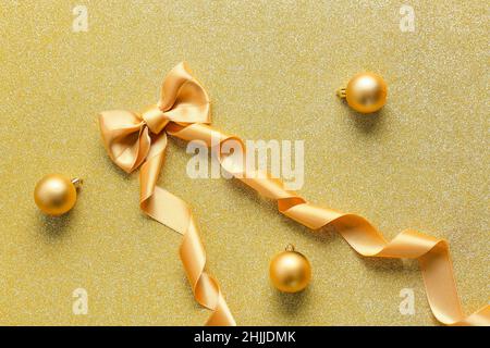 Goldene Schleife mit Weihnachtskugeln auf glänzendem Hintergrund Stockfoto