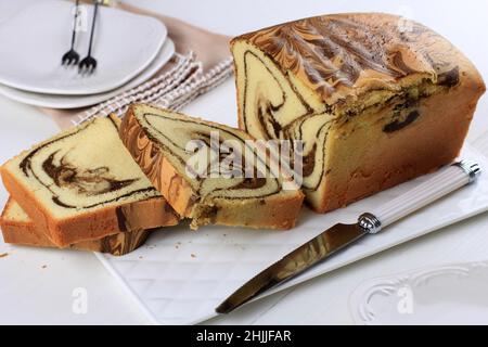 Brotscheiben-Marmorkuchen auf weißem Teller, Holztisch. Hausgemachte Backwaren Stockfoto