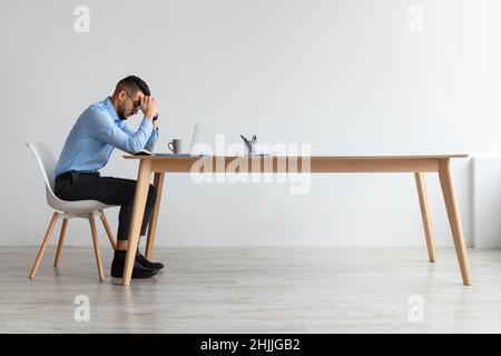 Arabischer Mann, der bei der Arbeit an Kopfschmerzen oder Migräne leidet Stockfoto