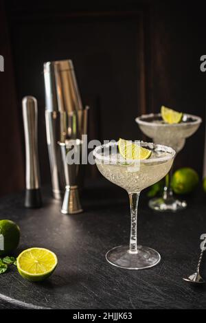 Margarita Cocktail mit Limette und Eis auf dunklem Holztisch mit Kopierfläche. Klassischer Margarita- und Daiquiri-Cocktail. Stockfoto