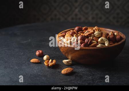 Gemischte Nüsse in einer Schüssel auf dunklem Holzhintergrund. Stockfoto