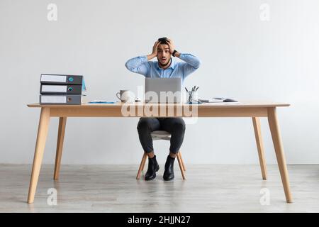 Schockiert arabischen Kerl greifen Kopf mit Laptop Stockfoto