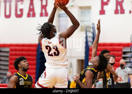 West Islip, New York, USA - 21. Januar 2022: Basketballspieler der High School schießen den Ball über die Verteidiger, die Gesichtsmasken unter ihren Kins tragen Stockfoto