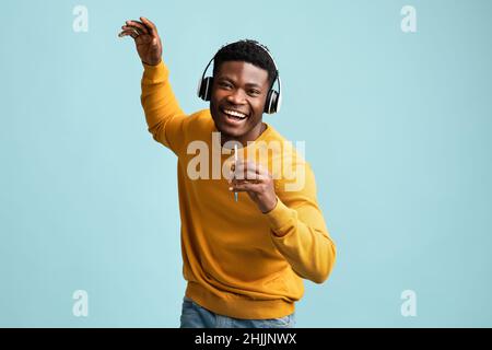 Schöner afroamerikanischer Mann mit Headset und Smartphone-Gesang Stockfoto