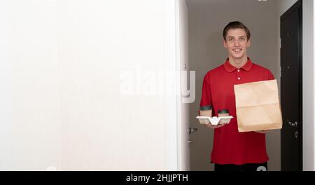 Essen und Kaffee Lieferung nach Hause, Lieferer mit Öko-Paket und Gläser americano vor der Haustür, Kurier in roten Uniform Bestellung Lebensmittel zum Mitnehmen Stockfoto