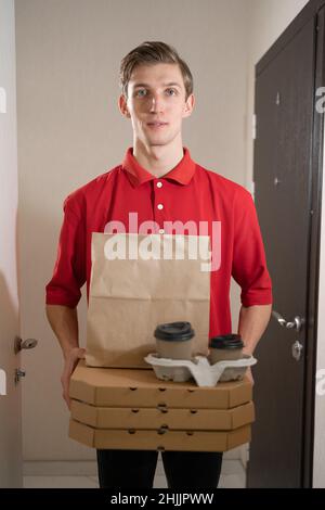 Lieferung von Pizza und Kaffee, Kurier mit Lebensmitteln und Kartons vor der Tür des Kunden, Essen zum Mitnehmen im Restaurant, Postbote mit Lebensmitteln Stockfoto