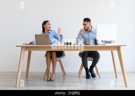 Kranker männlicher Angestellter hustet in Ellenbogen in der Nähe eines verängstigten Kollegen Stockfoto