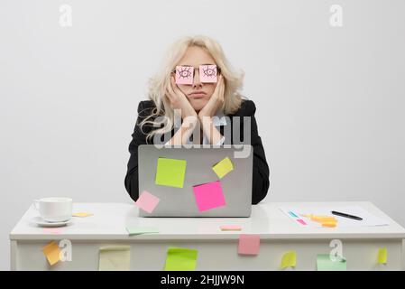 Workaholismus, Erschöpfung am Arbeitsplatz Konzept. Müde Geschäftsfrau mit Aufklebern mit offenen Augen Zeichnung auf Brille Stockfoto