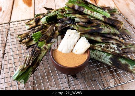 Gegrillter Fischkuchen aus gemahlenem Makrelenfisch, gemischt mit Gewürzen, dann in Bananenblätter gewickelt, über Holzkohle gegrillt, mit Erdnusssoße gegessen Stockfoto