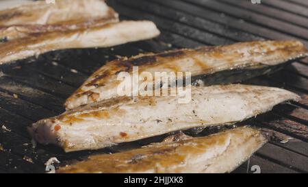 Nahaufnahme von gegrilltem Fisch. Aktion. Geschälter Fisch mit zartem Fleisch wird auf dem Grill gegart. Saftiger und schmackhafter Fisch wird auf dem Grill gegrillt. Kochen frisch f Stockfoto