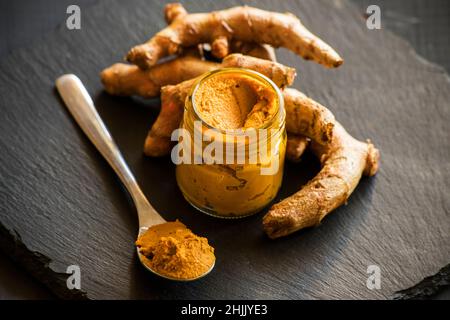 Kurkuma-Paste mit Kurkuma-Wurzel, Bestandteil der ajurvedischen Medizin goldene Milch Stockfoto