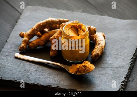 Kurkuma-Paste mit Kurkuma-Wurzel, Bestandteil der ajurvedischen Medizin goldene Milch Stockfoto