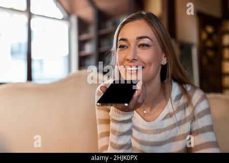 Porträt einer glücklichen Frau mit Sprachassistent auf dem Handy Stockfoto