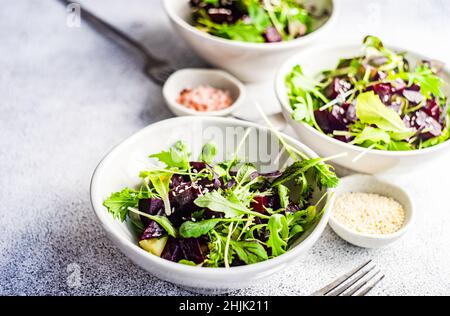 Drei Schalen gegrillter Rote Beete mit gemischtem Blattsalat und Sesam Stockfoto