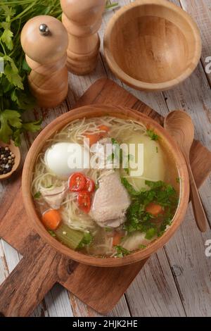 Südamerikanische Hühnernudelsuppe Caldo de Gallina mit gekochtem Ei und Kräutern. Die klassische peruanische Hühnernudelsuppe. Stockfoto