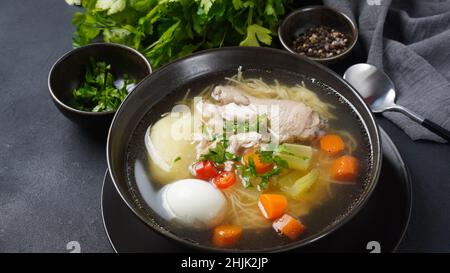 Südamerikanische Hühnernudelsuppe Caldo de Gallina mit gekochtem Ei und Kräutern. Die klassische peruanische Hühnernudelsuppe. Stockfoto