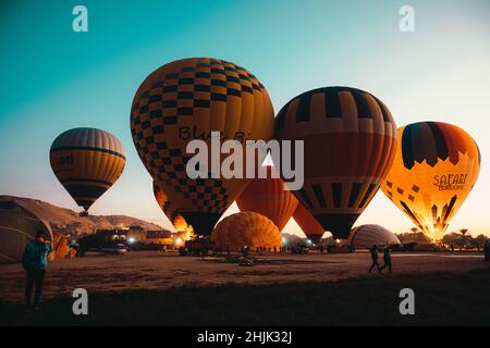 Luxor Ägypten Januar 2022 Blick auf viele Ballons auf dem Boden in luxor. Atemberaubende Aussicht während des Sonnenaufgangs, wenn Ballons aufsteigen und die Leute sie gehen sehen Stockfoto