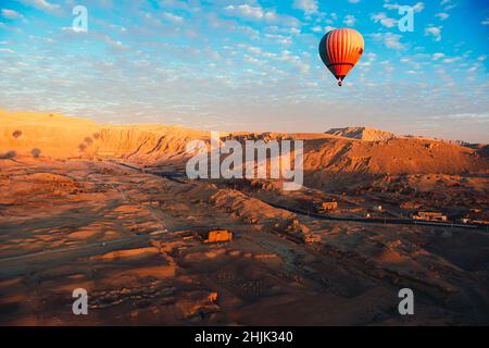 Fantastische Aussicht von einem heißluftballon in luxor, einem einzigen orangefarbenen Ballon in der Luft über die Wüstengegend. Tal der Könige und Königinnen in der Ferne. Stockfoto
