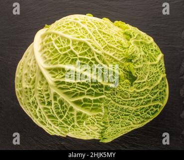 Ein Sproß aus Bio-Wirsing auf einem Schieferstein, Makroaufnahme, Draufsicht. Stockfoto