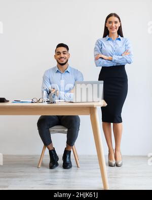 Porträt Eines Lächelnden Mannes Am Schreibtisch, Frau Im Stehen Stockfoto