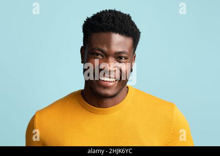 Porträt eines schönen afroamerikanischen Mannes, der auf Blau posiert Stockfoto