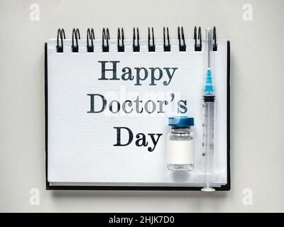 Alles gute zum Tag des Arztes. Spritzen, Injektionsfläschchen und ein Notizblock liegen auf dem Tisch. Nahaufnahme, drinnen, Ansicht von oben. Tageslicht, Studiofoto. Healthcar Stockfoto
