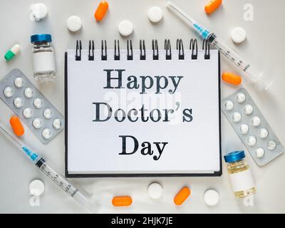 Alles gute zum Tag des Arztes. Spritzen, Injektionsfläschchen und ein Notizblock liegen auf dem Tisch. Nahaufnahme, drinnen, Ansicht von oben. Tageslicht, Studiofoto. Healthcar Stockfoto