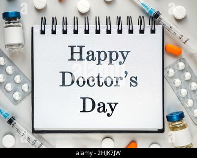 Alles gute zum Tag des Arztes. Spritzen, Injektionsfläschchen und ein Notizblock liegen auf dem Tisch. Nahaufnahme, drinnen, Ansicht von oben. Tageslicht, Studiofoto. Healthcar Stockfoto