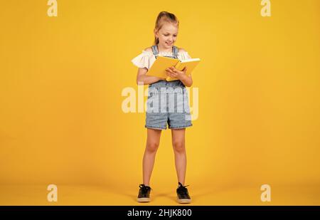 Nettes Kind geht, um Informationen aus dem Buch zu lesen, zurück zur Schule. Stockfoto