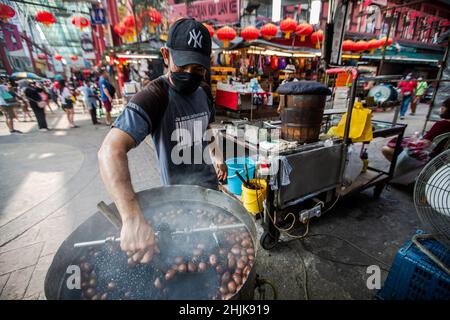 Kuala Lumpur, Malaysia. 30th Januar 2022. Ein Straßenhändler wird im Viertel Chinatown gesehen, wie er Kastanien röstet. Die malaysische Regierung hat die Aufhebung bestimmter Beschränkungen im Zusammenhang mit der chinesischen Neujahrsfeier angekündigt. (Foto von Wong Fok Loy/SOPA Images/Sipa USA) Quelle: SIPA USA/Alamy Live News Stockfoto