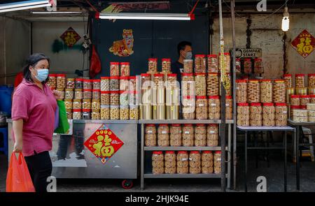 Kuala Lumpur, Malaysia. 30th Januar 2022. Eine Frau kommt im Chinatown-Viertel vor den Feierlichkeiten zum Neujahrsfest an einem Geschäft vorbei, in dem chinesische Neujahrskekse verkauft werden. Das Mondneujahr fällt auf den 1. Februar, und willkommen das Jahr des Tigers wird in China auf der ganzen Welt gefeiert. (Bild: © Wong Fok Loy/SOPA Images via ZUMA Press Wire) Bild: ZUMA Press, Inc./Alamy Live News Stockfoto